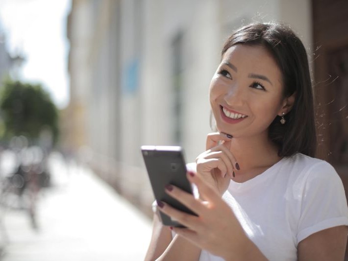 Young woman outdoors holding her smartphone